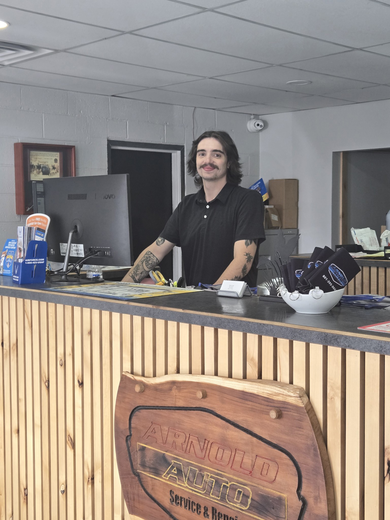 Smiling man standing behind the reception desk at Arnold Auto Service & Repair, ready to assist.